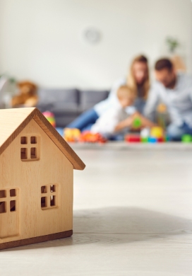 Maison miniature en bois posée devant une famille assise au salon