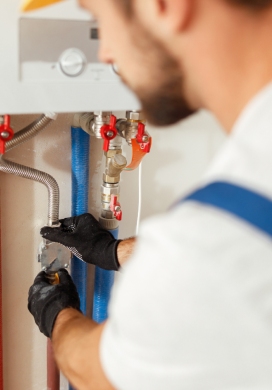 Technicien vérifiant les raccordements d'une chaudière et installation gaz